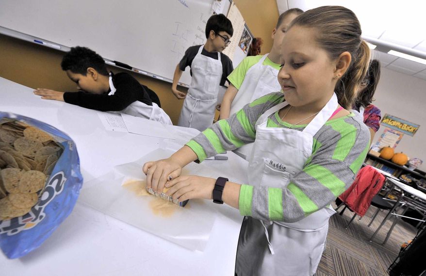 In this Jan. 19, 2017 photo, Maddie Lee, 10, learns to use a can of soup as a rolling pin during the first meeting of the Quick Fixin' Young Chefs Club winter session at the Fort Dodge Middle School, in Fort Dodge, Iowa. The popular club gives students a chance to learn basic cooking skills. (Hans Madsen/The Messenger via AP)