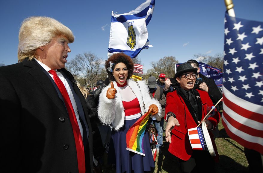 Supporters of President Donald Trump, from left, comedian Dustin Gold from Nashville Tenn., singer Joy Villa and fashion designer Andre Soriano, cheer during a rally organized by the North Carolina-based group Gays for Trump, at the National Mall near the Washington Monument in Washington, Saturday, March 4, 2017. The speakers at the rally talked about immigration, gay rights, and several other issues and later marched from the National Mall to the White House. (AP Photo/Manuel Balce Ceneta)