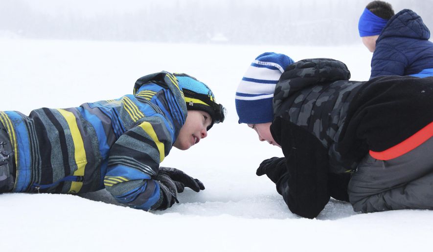 ADVANCE FOR WEEKEND MARCH 4-5, 2017 AND THEREAFTER - In this Feb. 24, 2017 photo, third grader Ryder Lagerson, left, uses his headlight to help his Kaleidescope School of Arts and Sciences classmate Josiah Holloway, right, try to catch a fish during an ice fishing outing at Sport Lake in Soldotna, Alaska. Hundreds of students from multiple Kenai Peninsula School District schools take part in the Alaska Department of Fish and Game&#x27;s &amp;quot;Salmon in the Classroom&amp;quot; program each year, which includes three ice fishing outings in the winter. (Megan Pacer /Peninsula Clarion via AP)