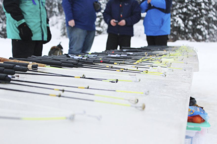 ADVANCE FOR WEEKEND MARCH 4-5, 2017 AND THEREAFTER - In this Feb. 24, 2017 photo, fishing poles rest on a table while volunteers wait for the next group of students from Kaleidescope School of Arts and Sciences at Sport Lake in Soldotna, Alaska, during one of three ice fishing outings put on by the Alaska Department of Fish and Game each winter. The ice fishing outings are part of the Department of Fish and Game's "Salmon in the Classroom" program that several classes throughout the Kenai Peninsula Borough School District take part in each year. (Megan Pacer/Peninsula Clarion via AP)