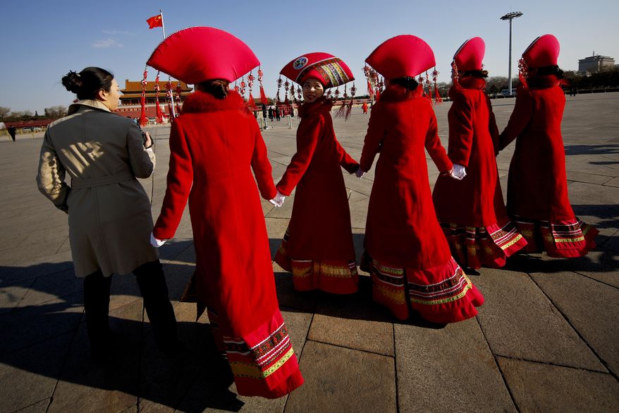 Bus ushers in ethnic minority costumes walk on Tiananmen Square during the opening session of the annual National People's Congress in Beijing, Sunday, March 5, 2017. China's top leadership as well as thousands of delegates from around the country are gathered at the Chinese capital for the annual legislature meetings. (AP Photo/Andy Wong)