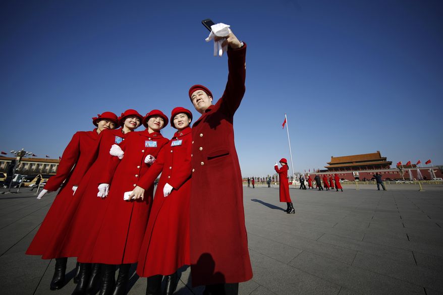 Bus ushers take a selfie on Tiananmen Square during the opening session of the annual National People's Congress in Beijing, Sunday, March 5, 2017. China's top leadership as well as thousands of delegates from around the country are gathered at the Chinese capital for the annual legislature meetings. (AP Photo/Andy Wong)