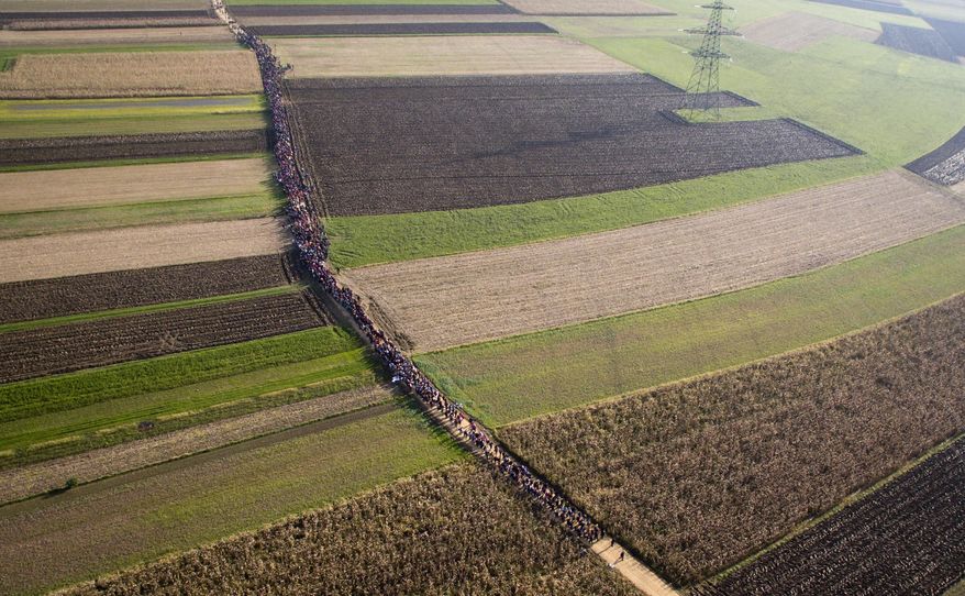 FILE - In this Oct. 25, 2015 areial view file photo, a column of migrants moves through fields after crossing from Croatia, in Rigonce, Slovenia. A German newspaper reports that the government planned to close the border with Austria and turn back asylum-seekers in September 2015, but nixed the plan at the last minute., the paper reported Sunday March 5, 2017. The interior ministry said in a statement it could “neither confirm nor deny” the report. (AP Photo/Darko Bandic.File)