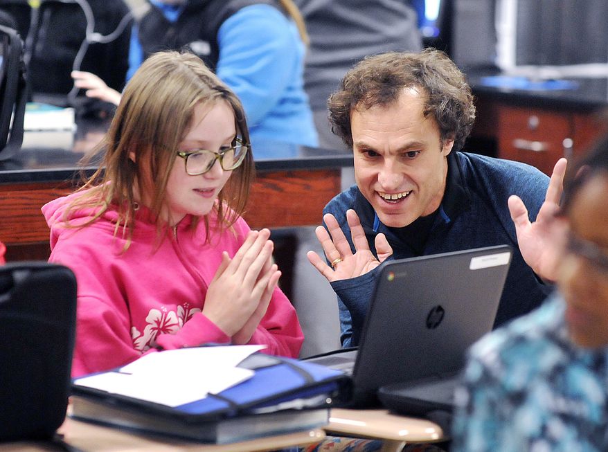 In a Thursday March 2, 2017 photo, Highland Middle School sixth-grader Aliyah Brewer reacts with Highland language arts instructional coach Joe Melo as he helps her find what she is looking for online from the Anderson Public Library on her school-assigned Chromebook, in Anderson, Ind. Highland students are learning how to use their new e-cards to access the public library's resources through a partnership program between the school and library. (John P. Cleary/The Herald-Bulletin via AP)
