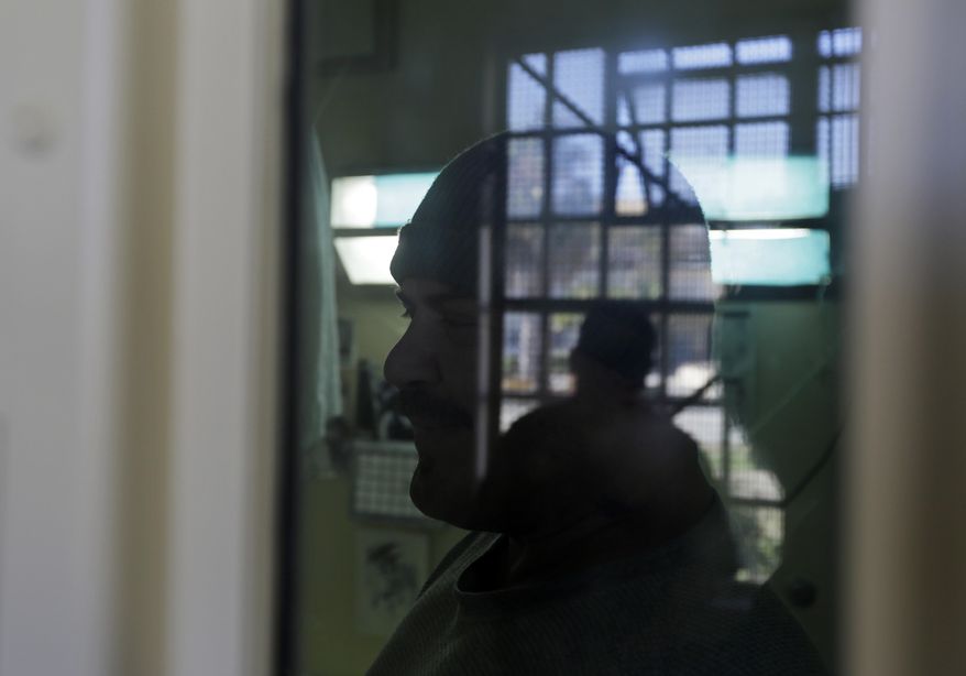 FILE - In this Aug. 16, 2016 file photo, Scott Pinholster stands in his cell in the adjustment center on death row at San Quentin State Prison in San Quentin, Calif. A settlement of a lawsuit by inmates against the state of California, obtained by The Associated Press, says the state no longer will keep inmates in the center just for being gang members. Inmates can still be sent to the windowless cells if they are considered an immediate danger. (AP Photo/Eric Risberg, File)