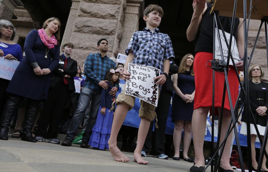 Max Briggle, right, holds a sign as he joins other members of the transgender community during a rally on the steps of the Texas Capitol, Monday, March 6, 2017, in Austin, Texas. The group is opposing a "bathroom bill" that would require people to use public bathrooms and restrooms that correspond with the sex on their birth certificate. (AP Photo/Eric Gay)