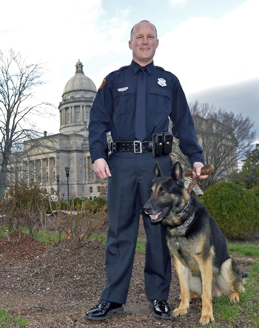 Officer Mike Lusardi and his K-9 partner Ernie pose outside the Kentucky State Capitol, Wednesday, March 1, 2017, in Frankfort, Ky. Ernie was shot and wounded in the line of duty but under current state law the accused can only be charged with a misdemeanor due to the dog being able to return to duty. (AP Photo/Timothy D. Easley)