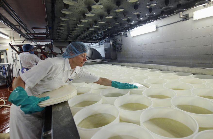 In this Feb. 27, 2017, photo, Brenda Patterson puts covers on wheels of Grand Cru Surchoix cheese so they can be pressed at the Emmi Roth USA production plant in Monroe, Wis. The company won the World Championship Cheese Contest in 2016 for the cheese and since then has seen an increase in sales of the cheese. The contest is organized by the Wisconsin Cheese Makers Association, which also organizes the United States Championship Cheese Contest that runs until March 9 in Green Bay, Wis. The contests are in alternate years. (AP Photo/Carrie Antlfinger)