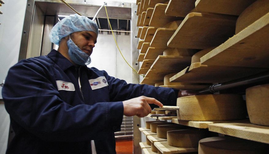 In this Feb. 27, 2017, photo, Jon Conkey cuts a piece from a wheel of Grand Cru Surchoix cheese at the Emmi Roth USA production plant in Monroe, Wis., for labeling. The company won the World Championship Cheese Contest in 2016 for the cheese and since then has seen an increase in sales of the cheese. The contest is organized by the Wisconsin Cheese Makers Association, which also organizes the United States Championship Cheese Contest that runs until March 9 in Green Bay, Wis. The contests are in alternate years. (AP Photo/Carrie Antlfinger)