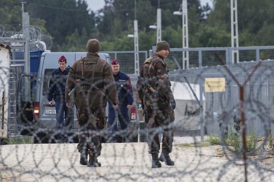 FILE - In this Sept. 21, 2016 file photo Hungarian soldiers, front, and police officers patrol at the transit zone at Hungary's southern border with Serbia near Tompa, 169 km southeast of Budapest, Hungary. Hungary's Prime Minister Viktor Orban, an early supporter of U.S. President Donald Trump, has ordered the reinforcement of fences on Hungary’s southern borders to keep out migrants, many of whom are Muslims. (Sandor Ujvari/MTI via AP, file)