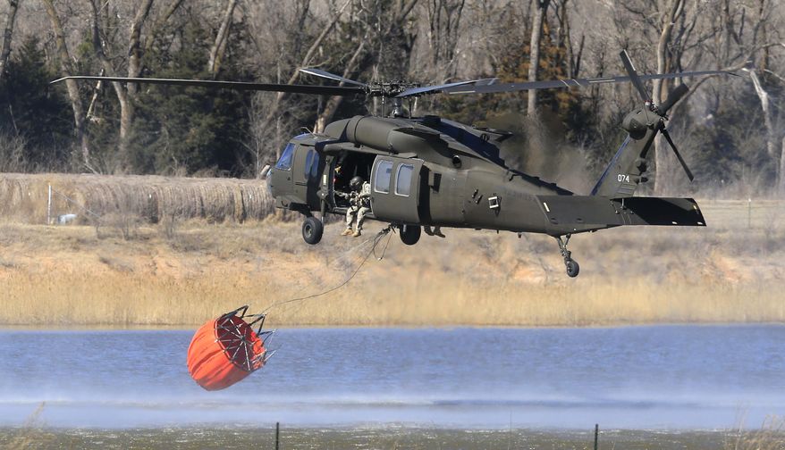 A National Guard helicopter picks up water from a farm pond near Hutchinson, Kan., Tuesday, March 7, 2017. Emergency crews on Tuesday struggled to contain deadly wildfires that have scorched hundreds of square miles of land in four states and forced thousands of people to flee their homes ahead of the wind-whipped flames. The fires were burning in parts of Kansas, Oklahoma, Texas and Colorado, and warnings that fire conditions were ripe were issued for Iowa, Missouri and Nebraska. (AP Photo/Orlin Wagner)