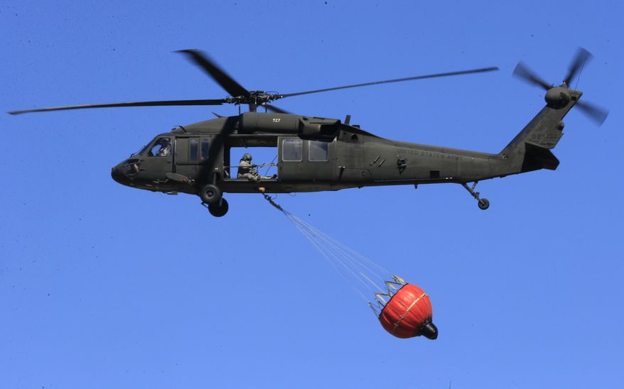 A National Guard helicopter flies to pick up water from a farm pond near Hutchinson, Kan., Tuesday, March 7, 2017. Emergency crews on Tuesday struggled to contain deadly wildfires that have scorched hundreds of square miles of land in four states and forced thousands of people to flee their homes ahead of the wind-whipped flames. The fires were burning in parts of Kansas, Oklahoma, Texas and Colorado, and warnings that fire conditions were ripe were issued for Iowa, Missouri and Nebraska. (AP Photo/Orlin Wagner)
