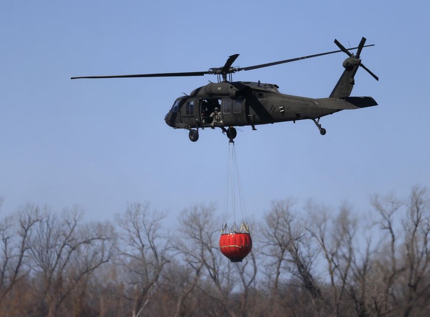 A National Guard helicopter carries water to a wildfire near Hutchinson, Kan., Tuesday, March 7, 2017. Emergency crews on Tuesday struggled to contain deadly wildfires that have scorched hundreds of square miles of land in four states and forced thousands of people to flee their homes ahead of the wind-whipped flames. The fires were burning in parts of Kansas, Oklahoma, Texas and Colorado, and warnings that fire conditions were ripe were issued for Iowa, Missouri and Nebraska. (AP Photo/Orlin Wagner)