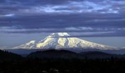 In this Nov. 29, 2016, photo, Oregon&#39;s Mount Hood, sporting a fresh coat of new snow, is lit through dispersing clouds by the setting sun as seen from Portland, Ore. (AP Photo/Don Ryan) **FILE**