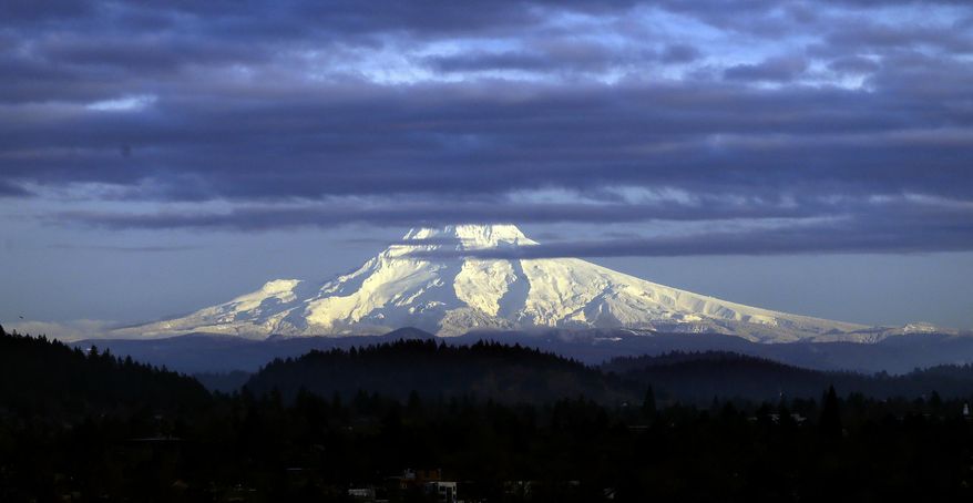 In this Nov. 29, 2016, photo, Oregon&#x27;s Mount Hood, sporting a fresh coat of new snow, is lit through dispersing clouds by the setting sun as seen from Portland, Ore. (AP Photo/Don Ryan) **FILE**