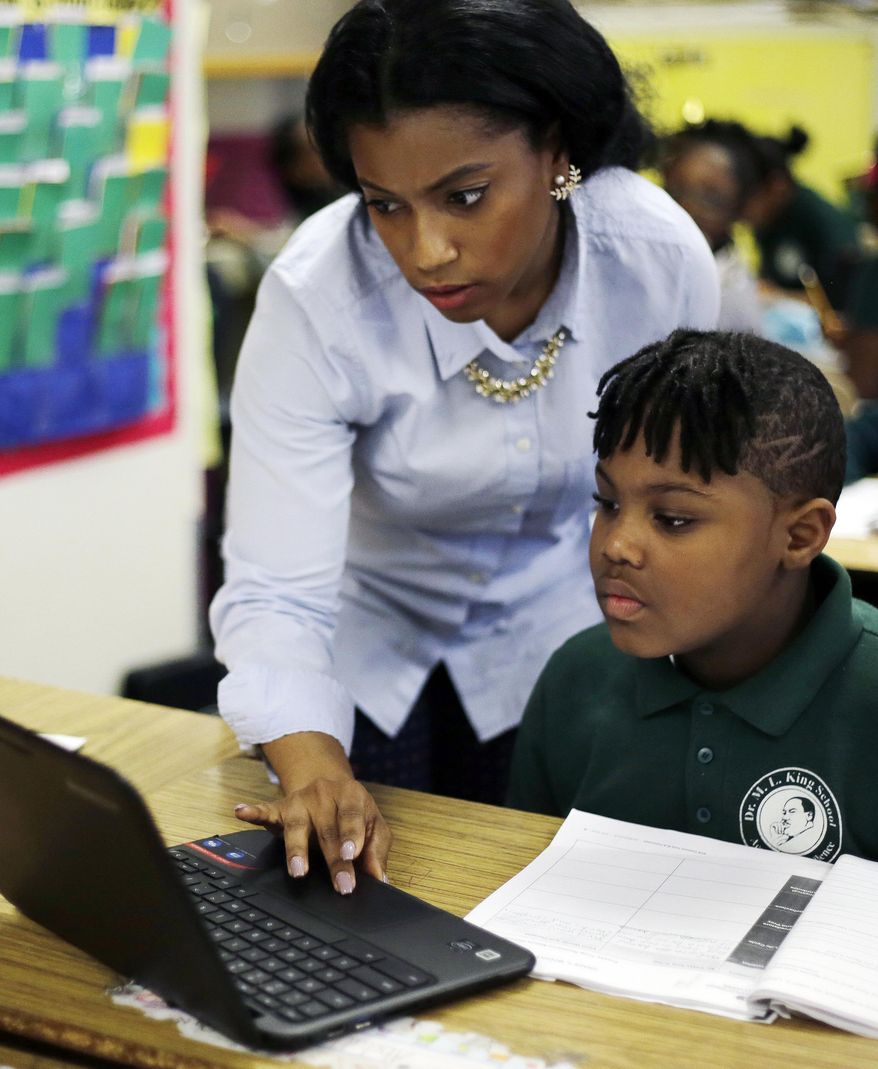 In this Feb. 23, 2017 photo, teacher Annika Edgerson helps Justin Beckles with a project in a third-grade classroom at the Martin Luther King Jr. Elementary School in Hartford, Conn. The city of Hartford has been hailed nationally as a school choice success story. Its magnet schools have promoted racial integration and new levels of academic achievement. For traditional public schools, such as Martin Luther King Jr., it’s a different story. (AP Photo/Elise Amendola)