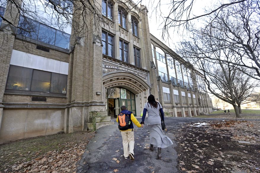 In this Feb. 23, 2017 photo, Natalie Langlaise walks with her son Justin toward the entrance of the Martin Luther King Jr. Elementary School in Hartford, Conn. Traditional public schools still educate about half the city’s children, but they are not moving in the same direction as magnet schools with racial integration and academic achievement. The disparities pain parents like Langlaise. “School days are supposed to be happy days,” Langlaise said. “It’s like, ‘Come on man, our kids deserve it, too.’” (AP Photo/Elise Amendola)