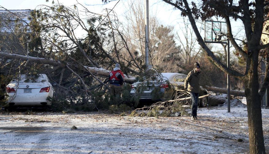 A family removes a tree from atop their cars after severe weather passed the area on Tuesday, March 7, 2017, in Orrock Township, Minn. Weather experts say a likely tornado touched down northwest of the Twin Cities, taking down trees and power lines and damaging buildings. (David Joles /Star Tribune via AP)