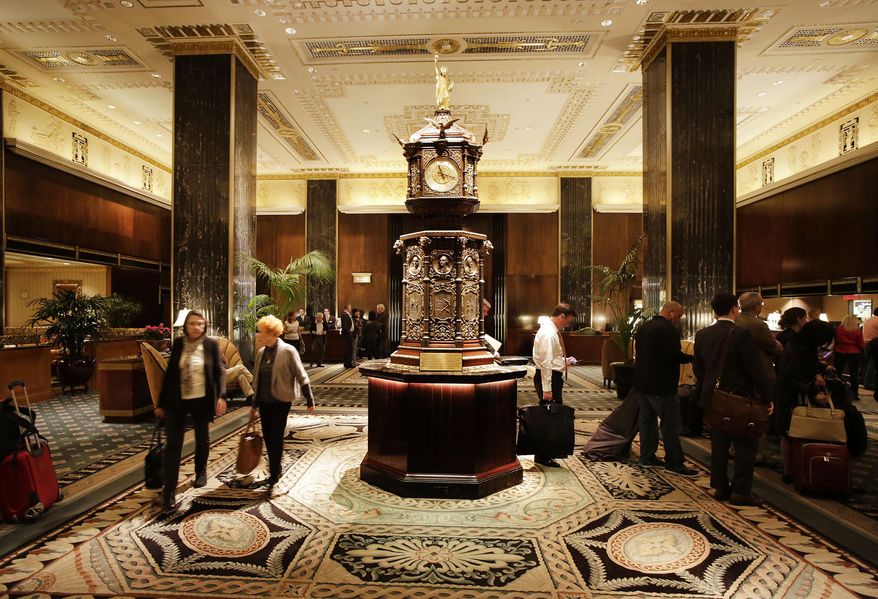 FILE - In this Oct. 6, 2014 file photo, guests pass through the wood-paneled main lobby featuring black marble pillars and ceiling reliefs, at the Waldorf Astoria hotel, in New York. New York City has landmarked historic interiors throughout the Waldorf Astoria to preserve them as the hotel's Chinese owners start a yearslong renovation. The Landmarks Preservation Commission voted Tuesday, March 7, 2017, to keep the Art Deco details in dozens of spaces in the grand Park Avenue building. (AP Photo/Mark Lennihan, FIle)