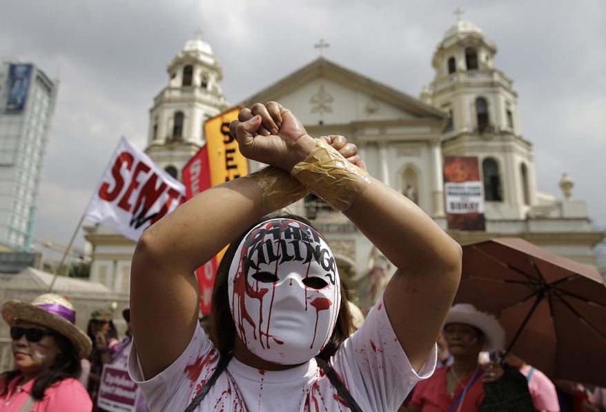 A protester wearing a mask joins a rally as they mark International Women's Day in Manila, Philippines on Wednesday March 8, 2017. The women's group is also opposing the revival of the death penalty by the Philippine Congress. (AP Photo/Aaron Favila)