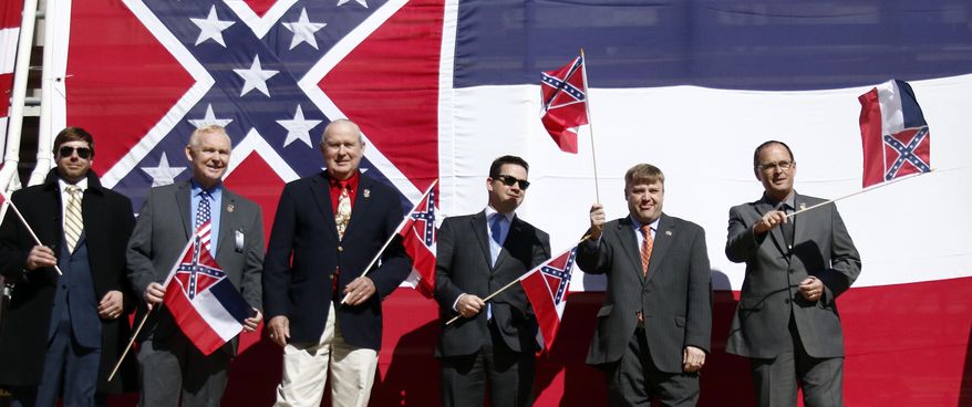 In this Jan. 16, 2016, file photo, a group of Mississippi flag supporting lawmakers, from left, Republican Reps. Robert Foster of Hernando, Dana Criswell of Olive Branch, Ken Morgan of Morgantown, Chris Brown of Nettleton, Bubba Carpenter of Burnsville and William Shirley of Quitman., pose in front of a large Mississippi state flag on the south steps of the Capitol in Jackson, Miss., during a rally sponsored by the Sons of Confederate Veterans and other groups in support of keeping the Confederate battle emblem on the state flag. Shirley wrote and presented a flag amendment attached to a universities finance bill that would withhold proposed tax exemptions to public universities that refuse to fly the state flag. (AP Photo/Rogelio V. Solis)