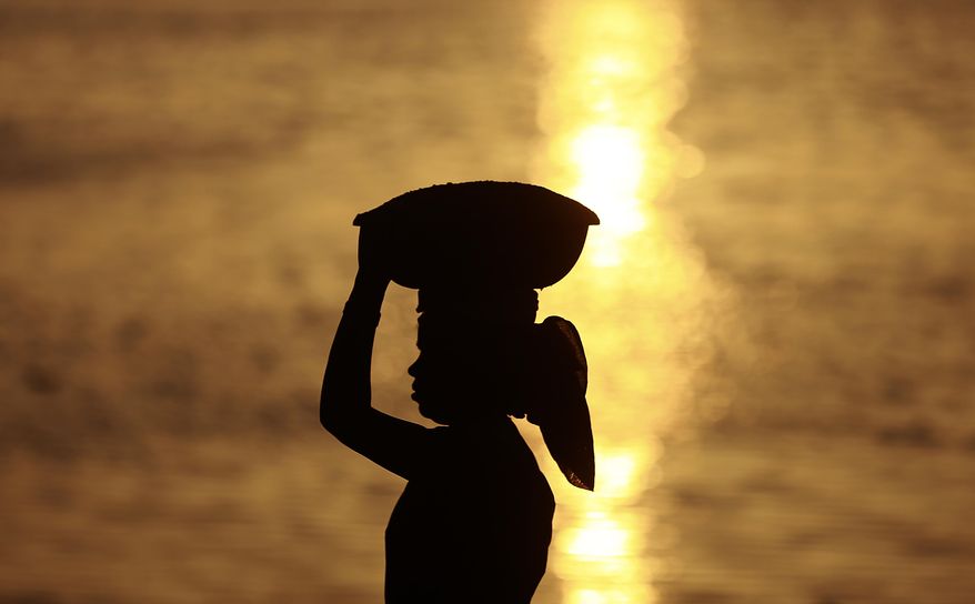 An Indian woman laborer carrying sand at a construction site is silhoutted against the Arabian Sea on International Women's Day in Mumbai, India, Wednesday, March 8, 2017. (AP Photo/Rafiq Maqbool)