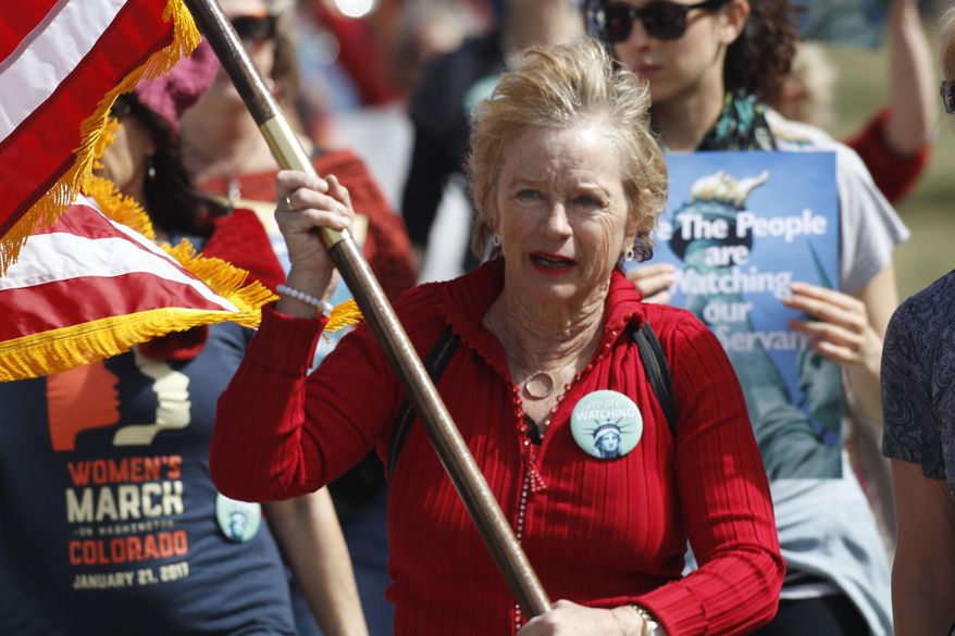 Helen Shreves of Denver carries the American flag as she leads protesters during a march around the State Capitol to mark International Women's Day on Wednesday, March 8, 2017, in Denver. More than 1,000 women--and men--took part in the Denver march, one of many staged across the country by organizers of January's Women's March. The action called on women to stay home from work and not spend money in stories or online to show their economic clout on America's fabric. (AP Photo/David Zalubowski)