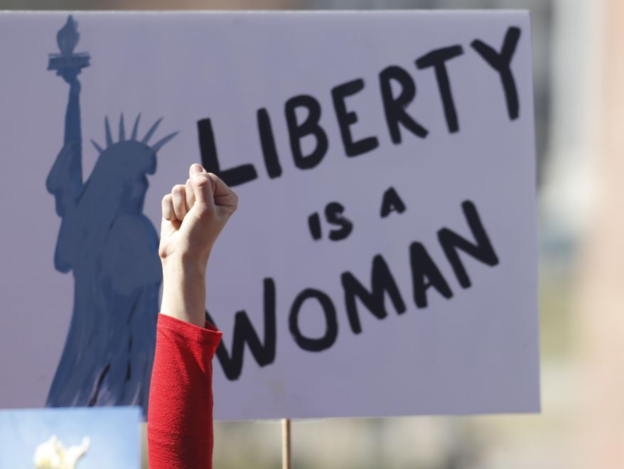 An unidentified participant raises her hand in support of a speaker during a march around the State Capitol to mark International Women's Day on Wednesday, March 8, 2017, in Denver. More than 1,000 women--and men--took part in the Denver march, one of many staged across the country by organizers of January's Women's March. The action called on women to stay home from work and not spend money in stories or online to show their economic clout on America's fabric. (AP Photo/David Zalubowski)