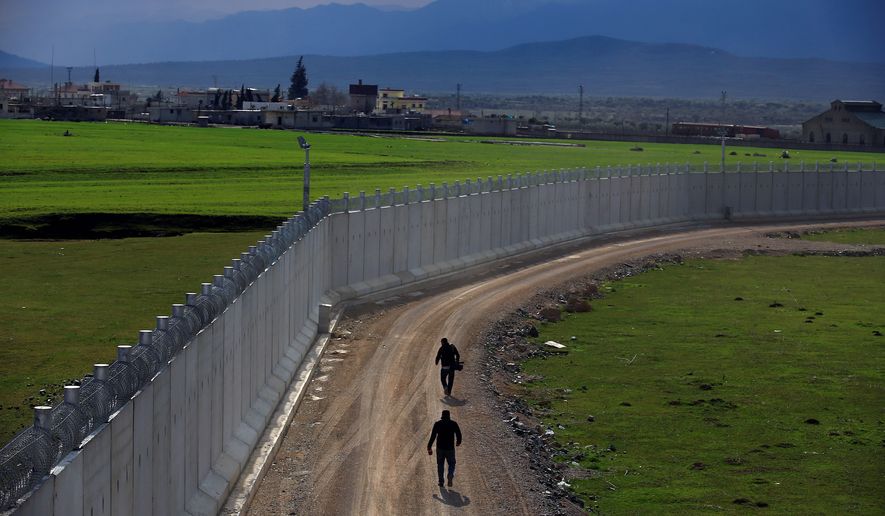 A Turkish army officer patrols a wall under construction near Kilis to help boost security along the border with conflict-stricken Syria. (Associated Press)