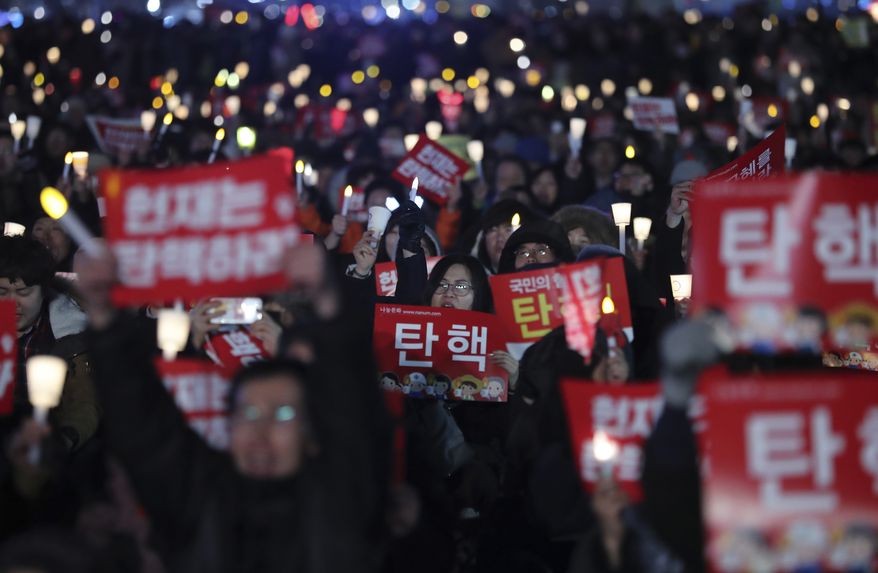 Protesters shout slogans during a rally calling for the impeachment of President Park Geun-hye in Seoul, South Korea, Thursday, March 9, 2017. South Korean President Park Geun-hye finds out Friday whether a court will remove her from office over a corruption scandal or allow her to complete her term. The letters read "Impeachment." (AP Photo/Lee Jin-man)