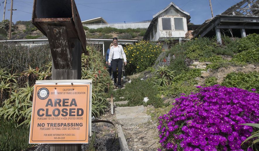 Crystal Cove Alliance President/CEO Alix Hobbs, front, and Executive Director Laura Davick, make their way from a house at Crystal Cove Cottages. More than a dozen dilapidated cottages at an oceanfront Southern California park will be renovated and made available for overnight rentals under a plan approved by the state Coastal Commission. Commissioners on Wednesday, March 8, 2017, unanimously approved a $30 million development permit to rebuild the wood cottages at Crystal Cove State Park. (Ana Venegas/The Orange County Register via AP)