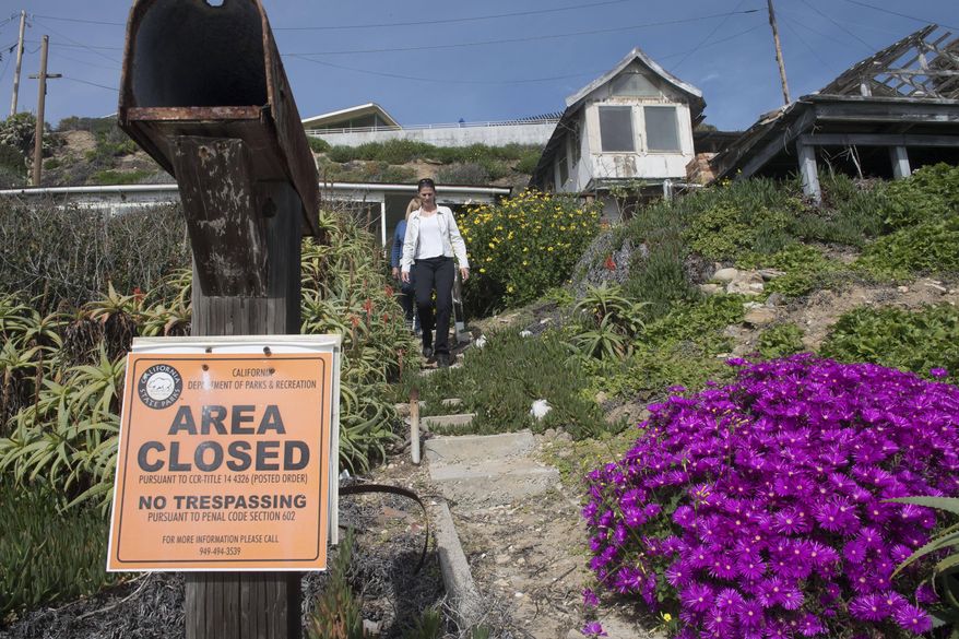 Crystal Cove Alliance President/CEO Alix Hobbs, front, and Executive Director Laura Davick, make their way from a house at Crystal Cove Cottages. More than a dozen dilapidated cottages at an oceanfront Southern California park will be renovated and made available for overnight rentals under a plan approved by the state Coastal Commission. Commissioners on Wednesday, March 8, 2017, unanimously approved a $30 million development permit to rebuild the wood cottages at Crystal Cove State Park. (Ana Venegas/The Orange County Register via AP)