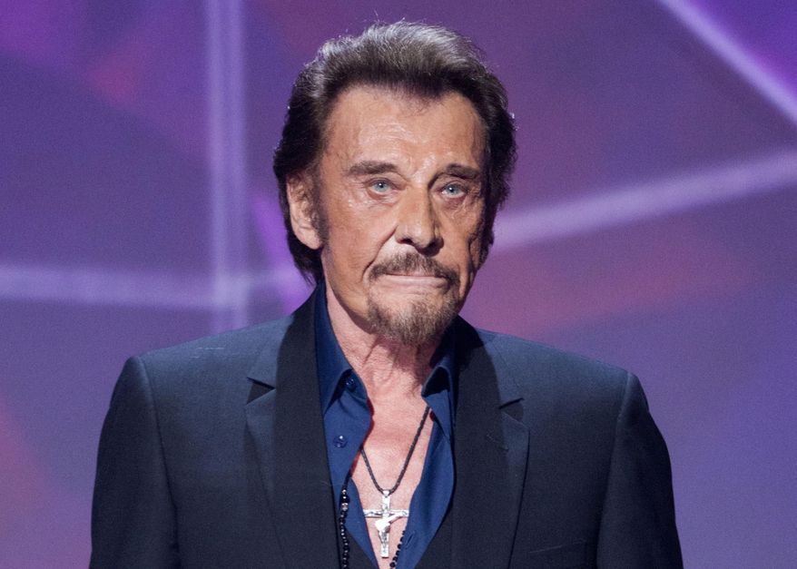 FILE - In this Friday, Feb. 12, 2016 file picture, French singer Johnny Hallyday gestures as he receives the best chanson album award during the 31st Victoires de la Musique, French music awards annual ceremony, in Paris, France. France's rock'n roll icon Johnny Hallyday says he is suffering from cancer but insists his condition is not life threatening, The 73-year-old singer, whose career spans over more than half a century, issued a statement late Wednesday after alarming rumors about his health emerged on social media. (AP Photo/Jacques Brinon, File)