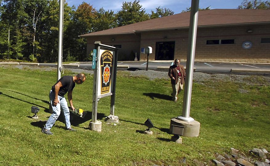 FILE - In this Sept. 14, 2014, file photo, a man places flowers in front of the Pennsylvania State Police barracks in Blooming Grove Township, Pa. Jury selection begins Thursday, March 9, 2017, in the capital murder trial of an anti-government sharpshooter charged with killing a Pennsylvania State Police trooper and critically wounding another in a 2014 ambush at their barracks. Thirty-three-year-old Eric Frein could face the death penalty if he’s convicted in the attack that killed Cpl. Bryon Dickson II and injured Trooper Alex Douglass. (Butch Comegys/The Times & Tribune via AP, File)