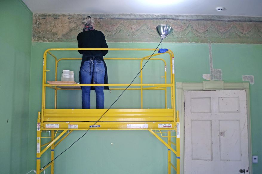 In this Nov. 23, 2016 photo provided by the Thomas Cole National Historic Site, art restoration expert Margaret Saliske uses scalpels and solvent to expose a decorative border in the east parlor of the home of artist Thomas Cole, in Catskill, N.Y. Not only did Cole paint mountainous landscapes that defined the Hudson River School. He painted on his parlor walls in Catskill. The decorative patterns near the ceiling lines had been covered over with many layers of paint and were hidden for more than a century before being discovered a few years ago. Now they are being restored and will be fully displayed when the Thomas Cole National Historic Site opens for the season in May 2017. (Jennifer Greim/Thomas Cole National Historic Site via AP)