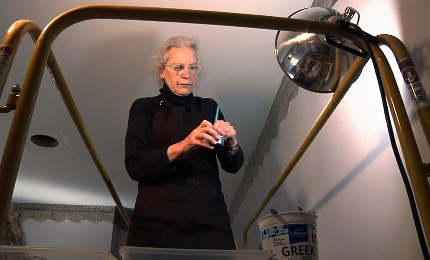 In this Feb. 27, 2017 image taken from video, art restoration expert Margaret Saliske prepares to work on restoring hand-painted borders at the home of artist Thomas Cole, in Catskill, N.Y. Not only did Cole paint mountainous landscapes that defined the Hudson River School. He painted on his parlor walls in Catskill. The decorative patterns near the ceiling lines, hidden under layers of paint for more than a century and discovered a few years ago, will be fully displayed when the Thomas Cole National Historic Site opens for the season in May. (AP Photo/Michael Hill)