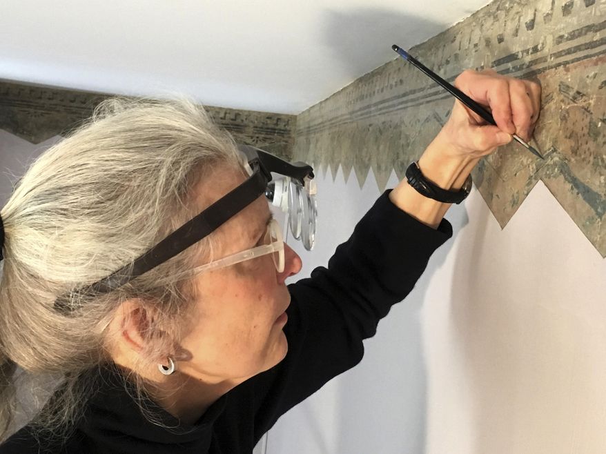 In this Feb. 27, 2017 photo, art restoration expert Margaret Saliske works on hand-painted borders at the home of artist Thomas Cole, in Catskill, N.Y. Not only did Cole paint mountainous landscapes that defined the Hudson River School. He painted on his parlor walls in Catskill. The decorative patterns near the ceiling lines, hidden under layers of paint for more than a century and discovered a few years ago, will be fully displayed when the Thomas Cole National Historic Site opens for the season in May. (AP Photo/Michael Hill)