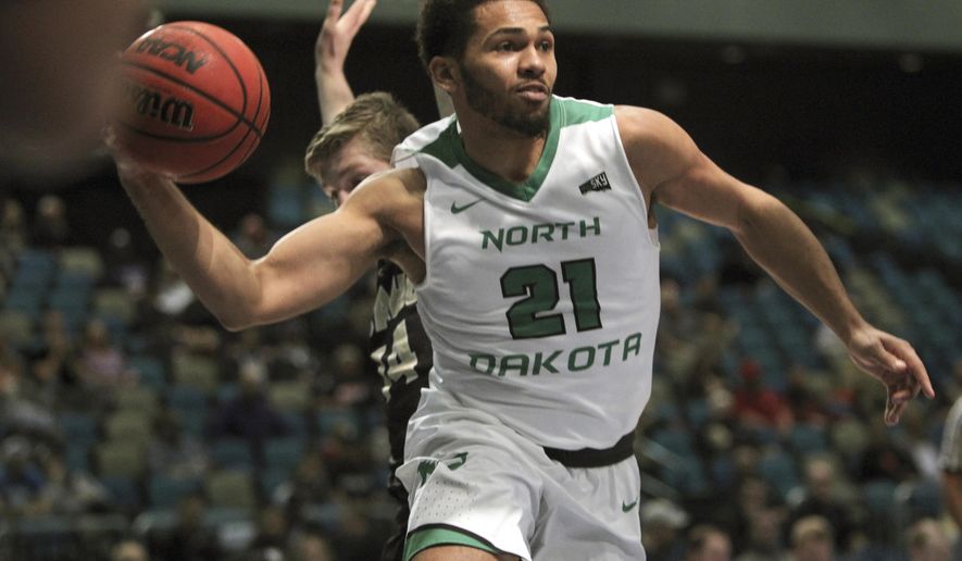 North Dakota guard Quinton Hooker (21) passes off under the basket against Idaho during the first half an NCAA college basketball game in the semifinals of the Big Sky tournament in Reno. Nev., Friday, March 10, 2017. (AP Photo/Lance Iversen)