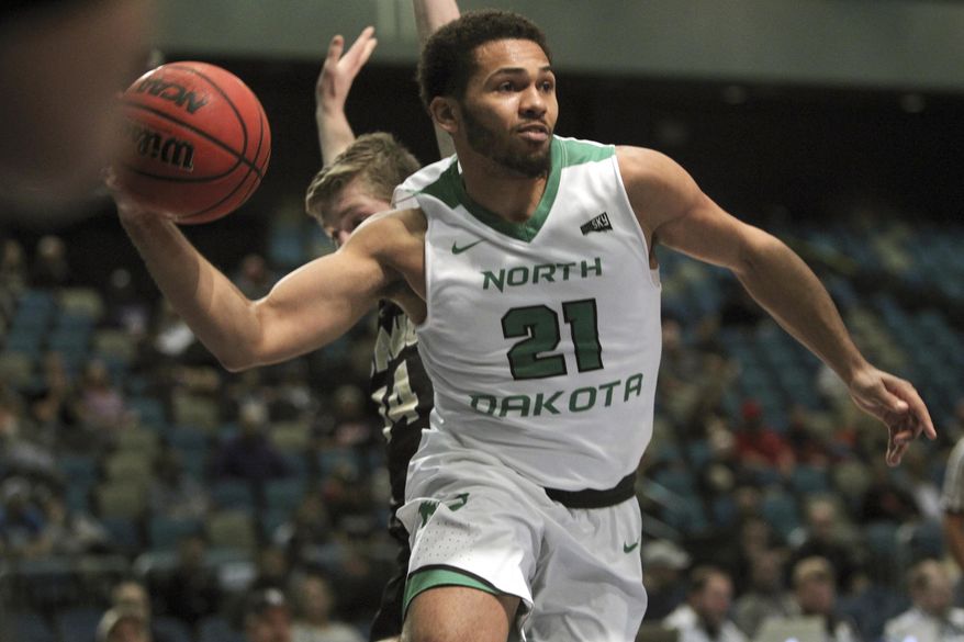 North Dakota guard Quinton Hooker (21) passes off under the basket against Idaho during the first half an NCAA college basketball game in the semifinals of the Big Sky tournament in Reno. Nev., Friday, March 10, 2017. (AP Photo/Lance Iversen)