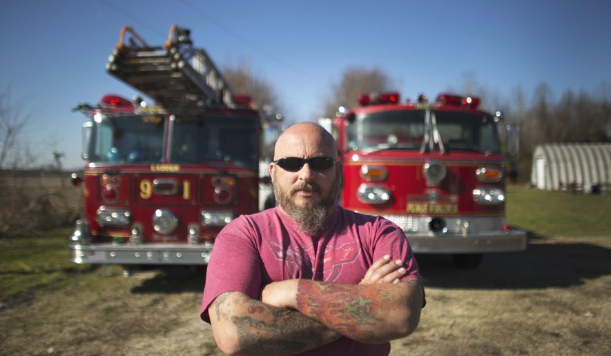 In this Feb. 19, 2017 photo, Jasen White stands in front of two of his antique firetrucks currently parked on a family members property in Virginia Beach, Va. White owns three antique firetrucks that he sometimes uses for community events, like Christmas parades. (L. Todd Spencer /The Virginian-Pilot via AP)