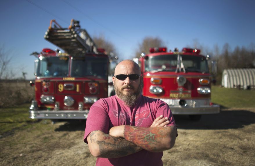 In this Feb. 19, 2017 photo, Jasen White stands in front of two of his antique firetrucks currently parked on a family members property in Virginia Beach, Va. White owns three antique firetrucks that he sometimes uses for community events, like Christmas parades. (L. Todd Spencer /The Virginian-Pilot via AP)