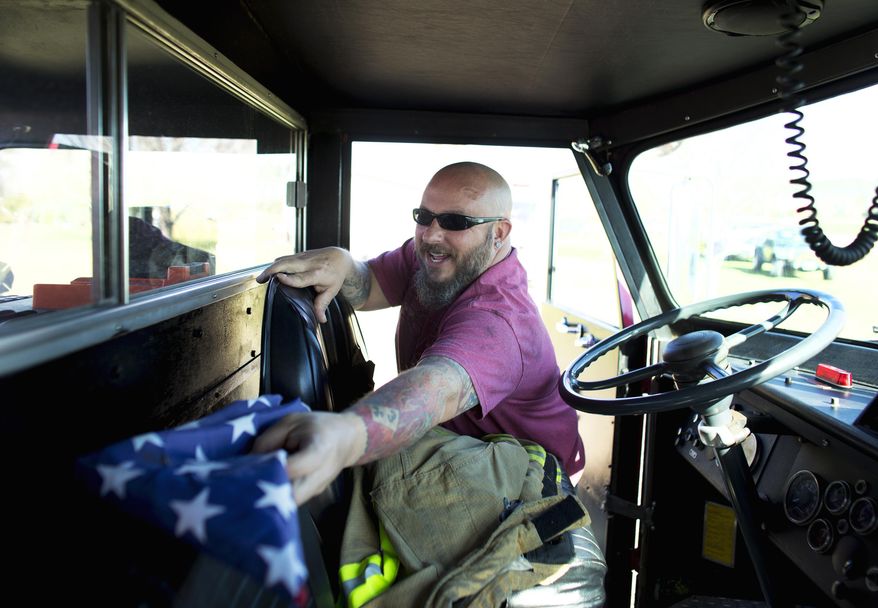In this Feb. 19, 2017 photo, Jasen White places an American flag in one of this firetrucks that he owns antique firetrucks currently parked on a family members property in Virginia Beach, Va. White owns three antique firetrucks that he sometimes uses for community events, like Christmas parades. (L. Todd Spencer/The Virginian-Pilot via AP)