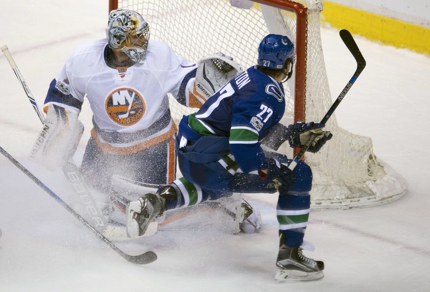 Vancouver Canucks defenseman Ben Hutton (27) fails to get a shot past New York Islanders goalie Thomas Greiss (1) during overtime in an NHL hockey game Thursday, March 9, 2017, in Vancouver, British Columbia. (Jonathan Hayward/The Canadian Press via AP)