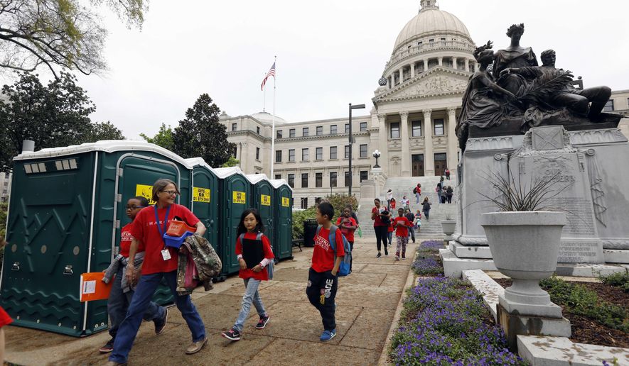 School children from Oxford, Miss., walk past the bank of portable toilets that are parked outside the Mississippi Capitol in Jackson, Miss., Friday, March 10, 2017. City residents are stocking up on bottled water and restaurants are evaluating whether they can stay open, the three days that a large portion of the city is expected to be without water or will experience low pressure because the city is replacing a major water pipe that's damaged. (AP Photo/Rogelio V. Solis)