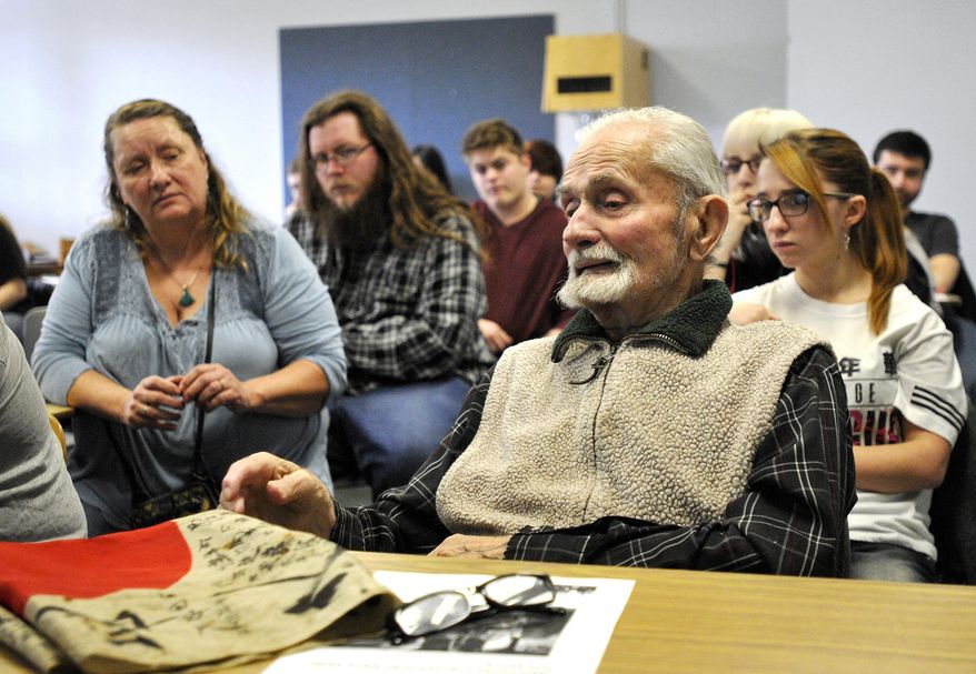 This Nov. 21, 2016 photo shows World War II veteran Marvin Strombo, right, talks to a Japanese Culture and Civilization class at the University of Montana in Missoula, Mont., about his experiences as a young Marine fighting in the Pacific during World War II. Strombo, 93, also brought a Japanese flag, on the desk in front of him, that he took from a slain Japanese officer in the Battle of Sapian that he's hoping can be returned to the man's family. (Tom Bauer/The Missoulian via AP)