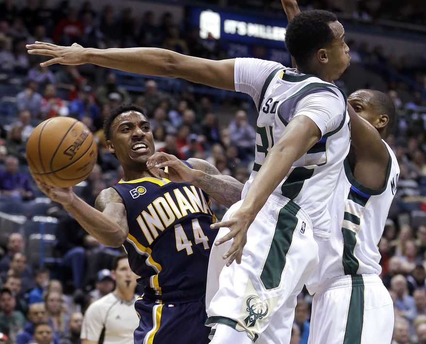 Indiana Pacers' Jeff Teague (44) passes around Milwaukee Bucks' John Henson, middle, and Khris Middleton, right, during the first half of an NBA basketball game Friday, March 10, 2017, in Milwaukee. (AP Photo/Aaron Gash)
