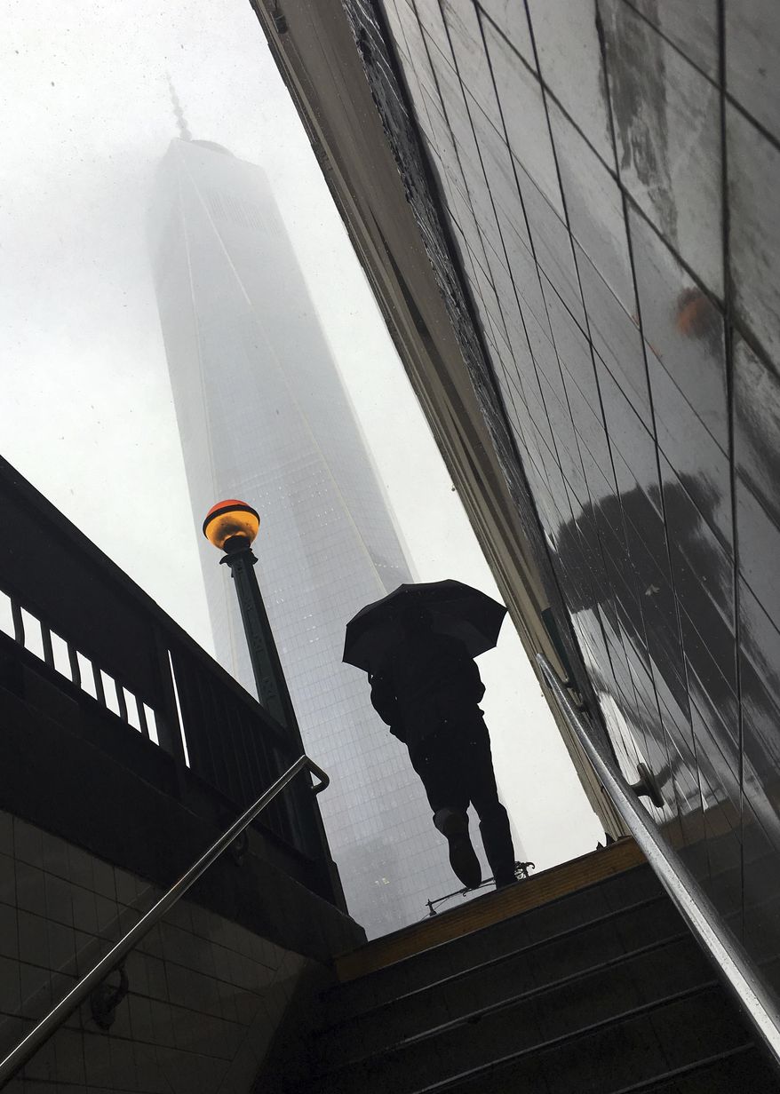 A morning commuter exits a subway station at Vesey Street in front of One World Trade Center in lower Manhattan as snow falls Friday, March 10, 2017, in New York. (AP Photo/Daniel P. Derrella