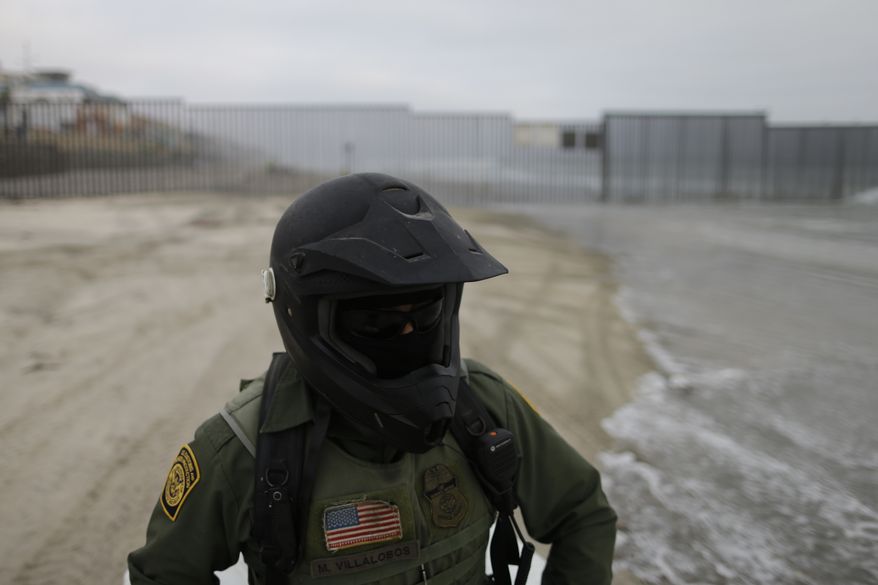 In this June 22, 2016, photo, a Border Patrol agent sits on a vehicle near where the border meets the Pacific Ocean in San Diego. (AP Photo/Gregory Bull)