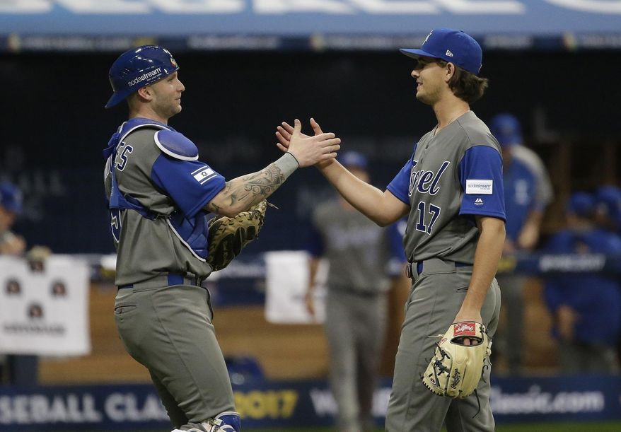 FILE - In this March 7, 2017 file photo, Israel's pitcher Dean Kremer, right, celebrates his team's victory with catcher Nick Rickles against Taiwan after the first round game of the World Baseball Classic at Gocheok Sky Dome in Seoul, South Korea. Team Israel is tearing up the World Baseball Classic, upsetting a trio of top 10 teams and generating a buzz with their plucky play, colorful fans and unusual mascot. But back in their supposed homeland, no one seems to be taking notice in a country where the game has long been overlooked as arcane and boring. The current team, made up almost entirely of American pros of Jewish descent, has been derided as a group of mercenaries will little connection to the country. (AP Photo/Ahn Young-joon)