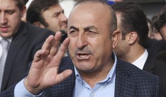 Turkish Foreign Minister Mevlut Cavusoglu, waves to supporters as he leaves after a campaign gathering in Metz, eastern France, Sunday, March 12, 2017. Foreign Minister Mevlut Cavusoglu was in France Sunday to whip up support for controversial constitutional reforms to expand the powers of the Turkish presidency. (AP Photo/Elyxandro Cegarra)